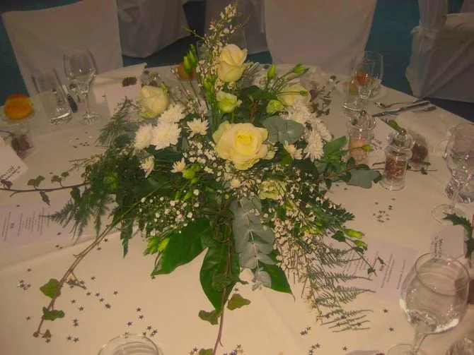 Grosses festliches Tischgesteck mit weissen Rosen und Efeuzweigen.